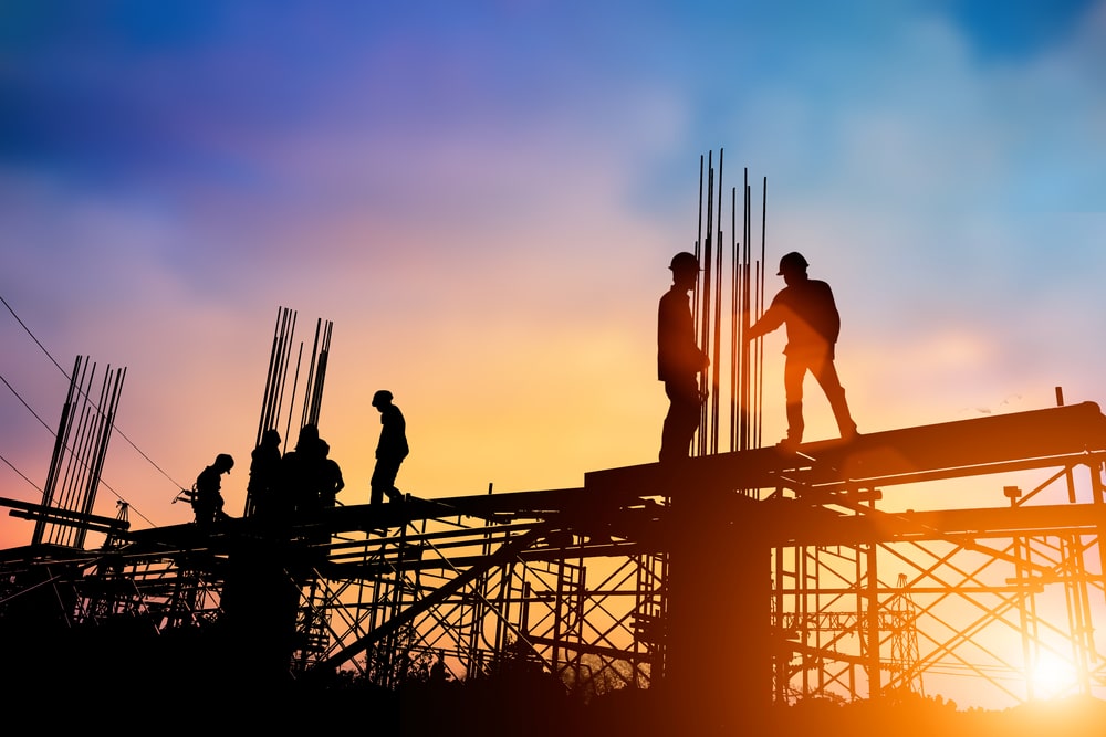 Silhouettes d'ouvriers sur un chantier au crépuscule